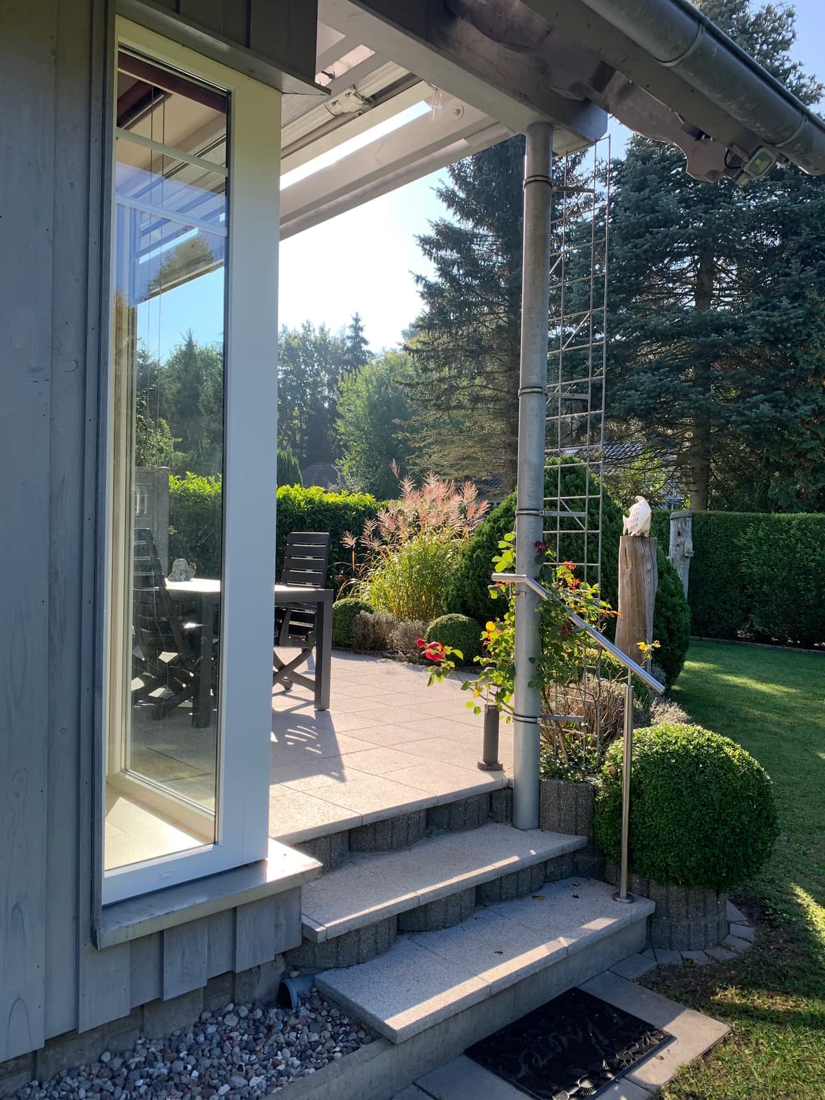 Stufen mit Handlauf hinauf zur Terrasse, daneben die Glasfront des Hauses