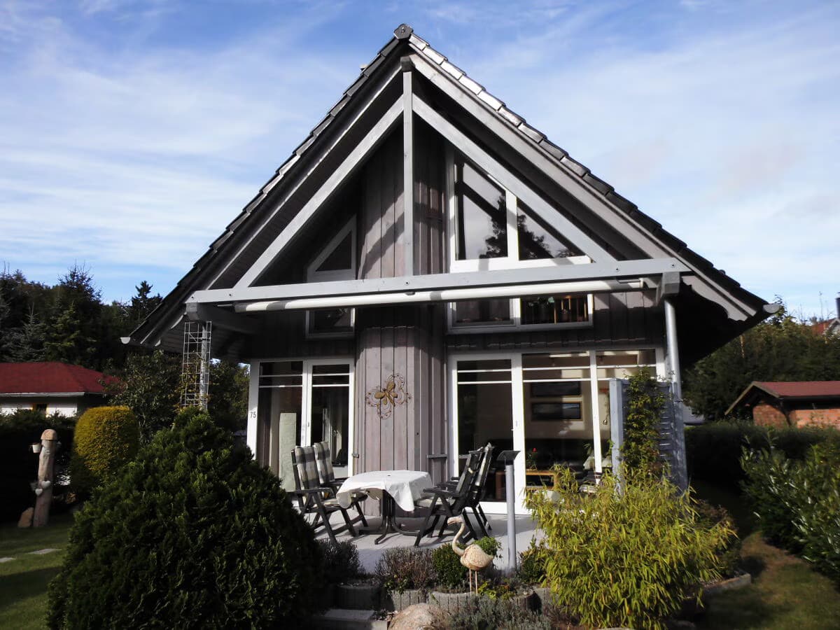 Südgiebel des Hauses mit überdachter Terrasse, Sitzgruppe und bodentiefen Fenstern